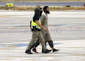GRA149 MELILLA, 26/09/2014.- El presunto líder de la célula terrorista vinculada al Estado Islámico (EI), detenido hoy en Melilla, custodiado por agentes de la Policía, a su llegada al aeropuerto de la ciudad autónoma desde donde ha sido trasladado a Madrid para su puesta a disposición del Juzgado Central de Instrucción número 3 de la Audiencia Nacional, que supervisa esta operación. EFE/NEUPIC/Fernando Gutiérrez