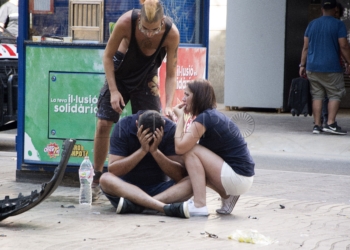 GRA180. BARCELONA, 17/08/2017.- Varios jóvenes permanecen junto a los restos de un vehículo, en el lugar del atropello masivo realizado por una furgoneta que ha arrollado esta tarde a varias personas que paseaban por las Ramblas de Barcelona. Los Mossos d'Esquadra y los equipos de emergencias sanitarias han desplegado un amplio dispositivo en esta zona, en el centro turístico de la capital catalana, frecuentada a diario por miles de turistas, que ha quedado acordonada. EFE/David Armengou
