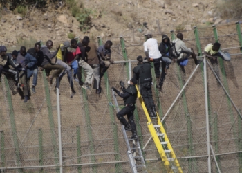 GRA059 MELILLA M 13/8/2014.- Dos de los inmigrantes encaramados a la valla de Melilla desde esta madrugada se han bajado de la verja y han sido entregados a Marruecos. Los dos subsaharianos han descendido por una de las escaleras colocadas por la Guardia Civil y, posteriormente, han sido entregados a las autoridades marroquíes por una de las puertas de acceso de la valla.El resto de subsaharinos, entre 60 y 70, permanecen subido en la parte alta del vallado, a una altura de seis metros, visiblemente cansados, tras siete horas.A ambos lados del perimetro, tanto en el lado español como en el marroquí, hay un fuerte despliegue policial.EFE/Francisco G. Guerrero