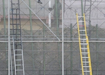 GRA009. MELILLA, 02/12/2014.- Varios subsaharianos permanecen encaramados en la valla de Melilla por la zona cercana al paso fronterizo de Barrio Chino, que está cortado al tránsito desde que a las siete de la mañana se hayan registrado dos intentos de entrada simultánea de dos grupos, con más de medio millar de inmigrantes. EFE/F. G. Guerrero