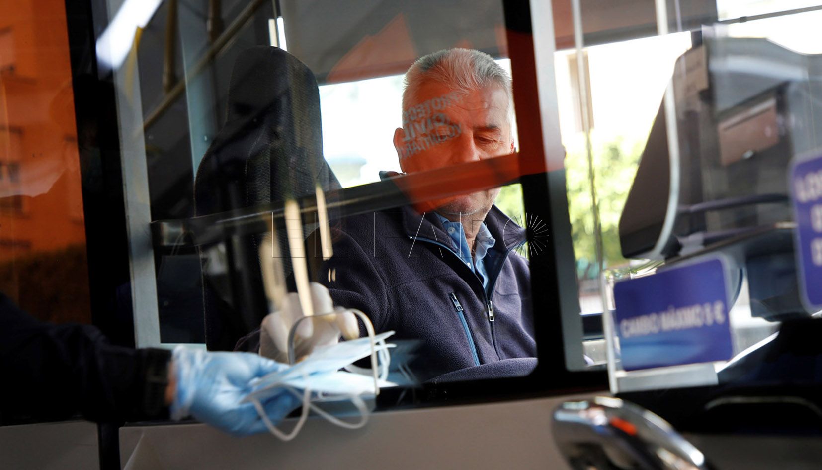 GRAF1096. MELILLA, 15/04/2020.- Un conductor de autobús coge una de las mascarillas durante su reparto que acaba este miércoles en regiones como Ceuta y Melilla tras el levantamiento de las restricciones de las actividades no esenciales decretadas ante la epidemia de coronavirus. EFE/F.G. Guerrero