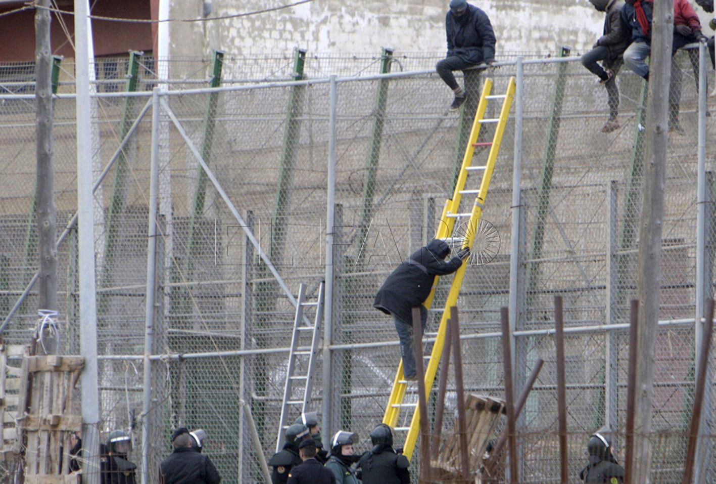 GRA122. MELILLA, 10/02/2015.- Varios de los inmigrantes encaramados a la valla de Melilla han decidido bajarse, tras permanecer en ella varias horas. Una decena de inmigrantes han permanecido encaramados en la valla de Melilla, en la zona del puesto fronterizo del Barrio Chino, donde hay un fuerte despliegue de la Guardia Civil, después de que un grupo de unos veinte subsaharianos haya conseguido acceder a la ciudad autónoma, en una noche en la que unas 400 personas, organizadas en grupos, han realizado varios conatos de salto en el perímetro fronterizo. EFE/Francisco Gª Guerrero