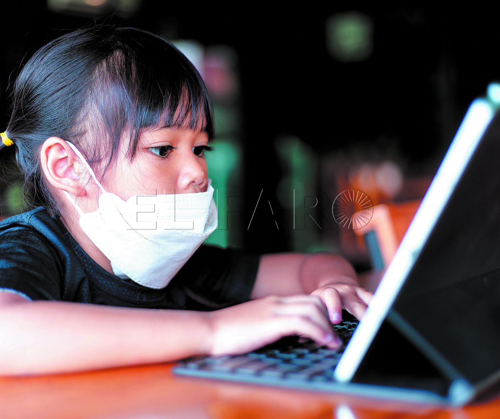 Happy Asian Child girl looks at tablet on the table