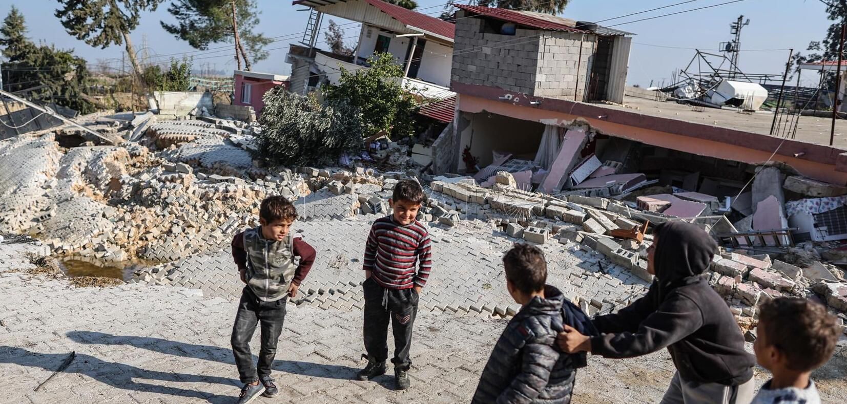 Hatay (Turkey), 22/02/2023.- Children play in front of buildings collapsed by a fault line in Demirkopru village, Hatay district, Turkey 22 February 2023. The fault line follows a 6.3-magnitude earthquake, according to U.S. Geological Survey, that hit the Syria-Turkey border on 20 February, weeks after a 7.8-magnitude earthquake hit the region on 06 February, killing more than 46,000 people. (Terremoto/sismo, Siria, Turquía) EFE/EPA/ERDEM SAHIN