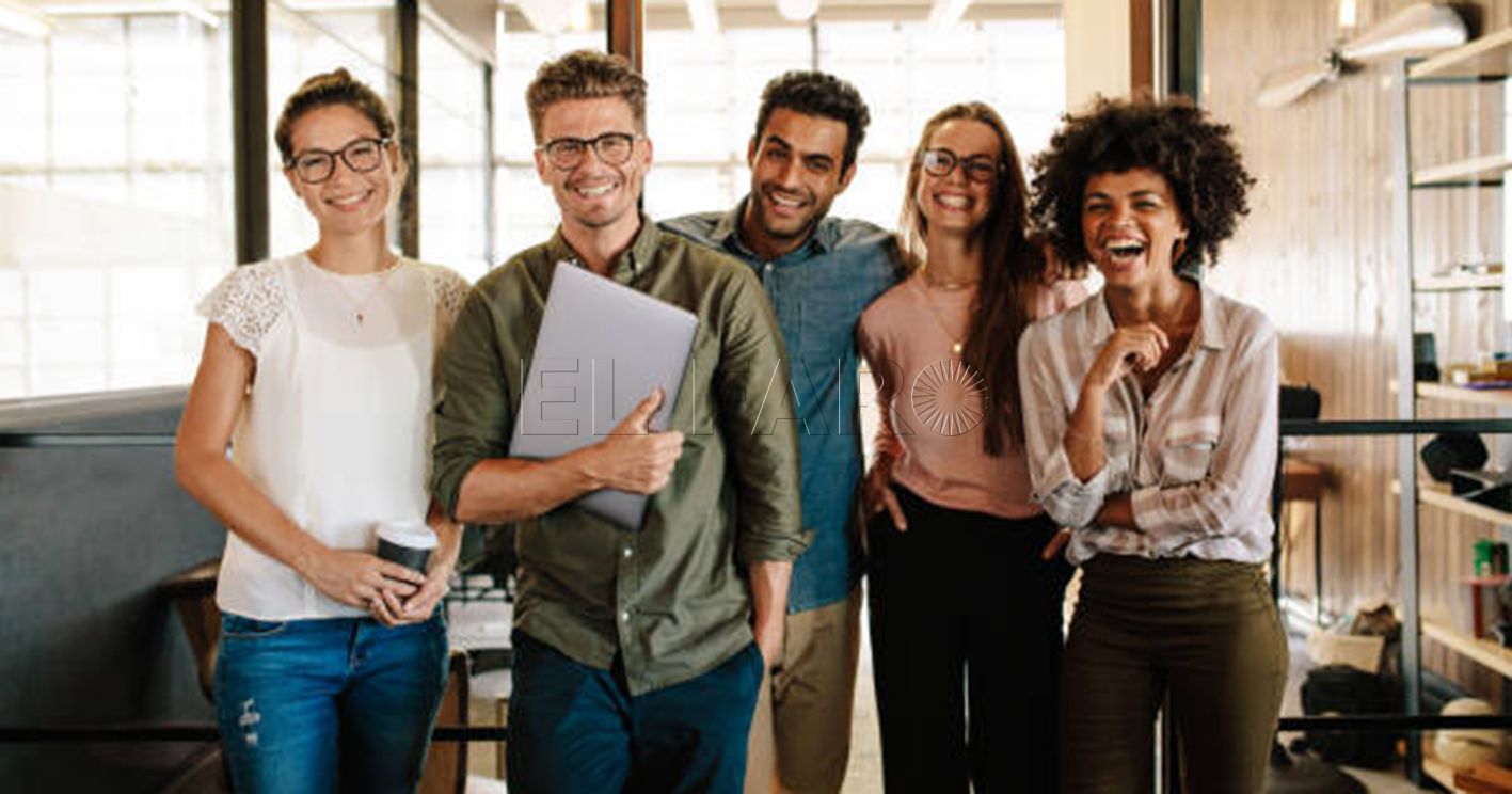 Portrait of creative business team standing together and laughing. Multiracial business people together at startup.