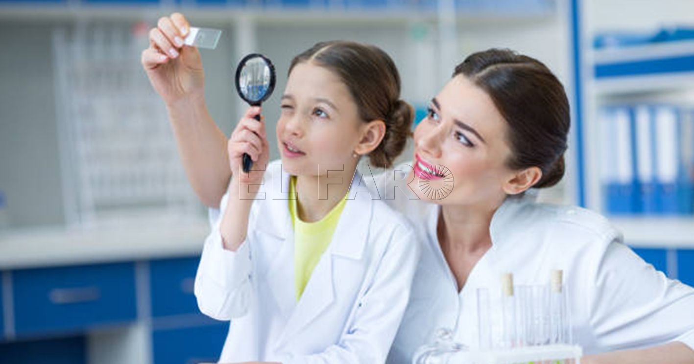 Woman teacher and girl student scientists looking at glass microscope slide through magnifier
